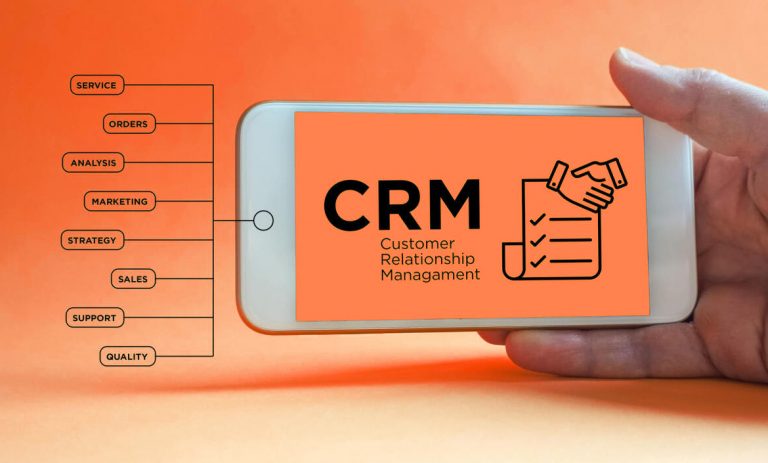 A hand holding a smartphone displaying a 'CRM Customer Relationship Management' interface with colorful graphics on a bright orange background. The phone screen showcases a customer handshake icon and checklist, symbolizing CRM functions, with service categories listed in a flowchart to the left side.