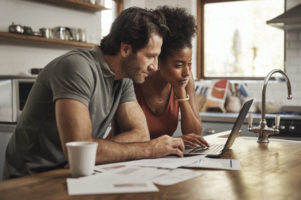 Couple reviewing financial details on a laptop in a home environment.