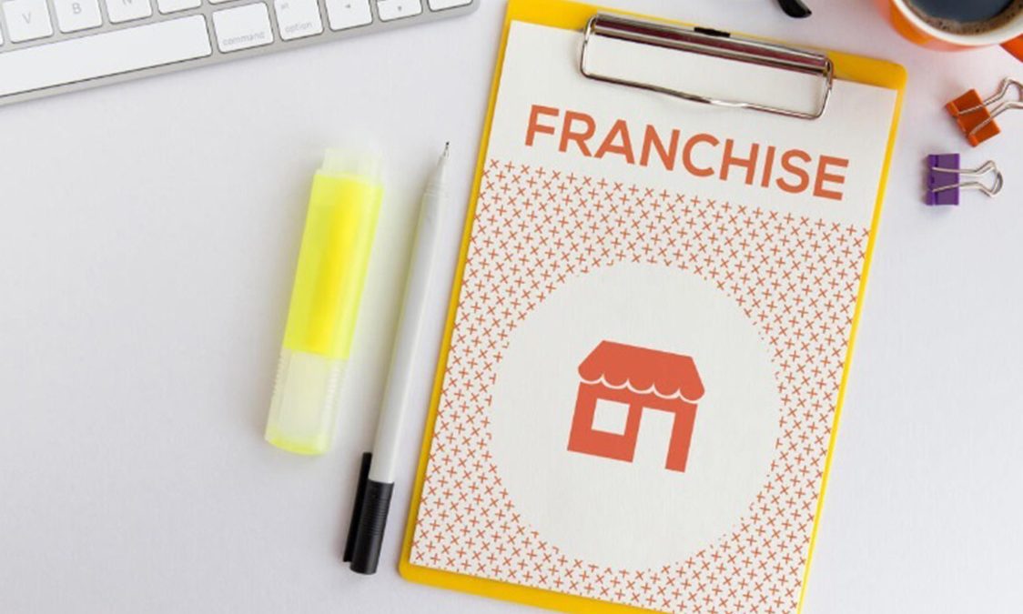 Clipboard with 'FRANCHISE' text and office supplies on a desk.